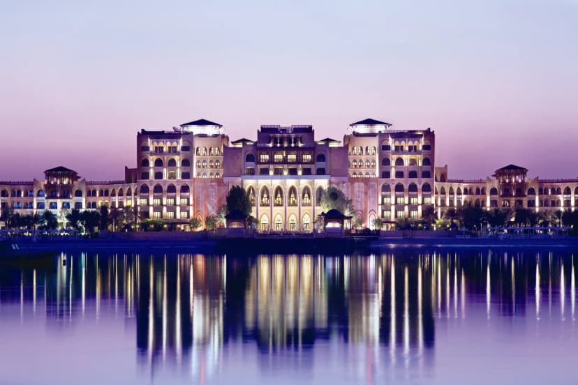 Hotel facade of Shangri-La Qaryat Al Beri Abu Dhabi at twilight, featuring arched windows, symmetrical design, and waterfront