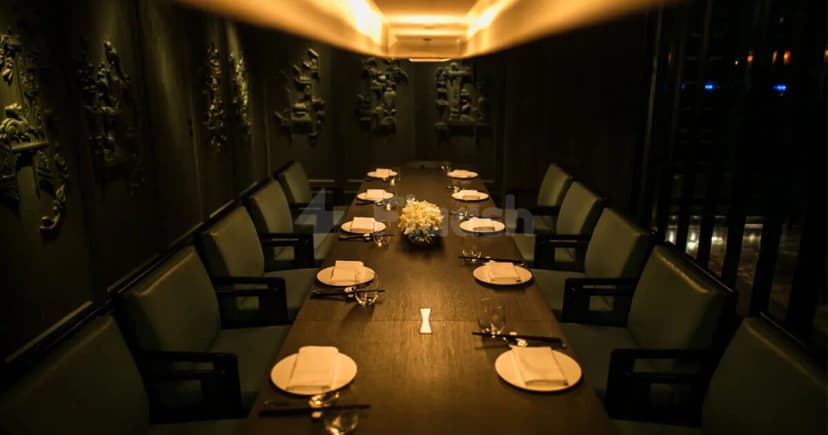 Long wooden dining table set for eight at Hakkasan Abu Dhabi, featuring ornate wall carvings and warm recessed