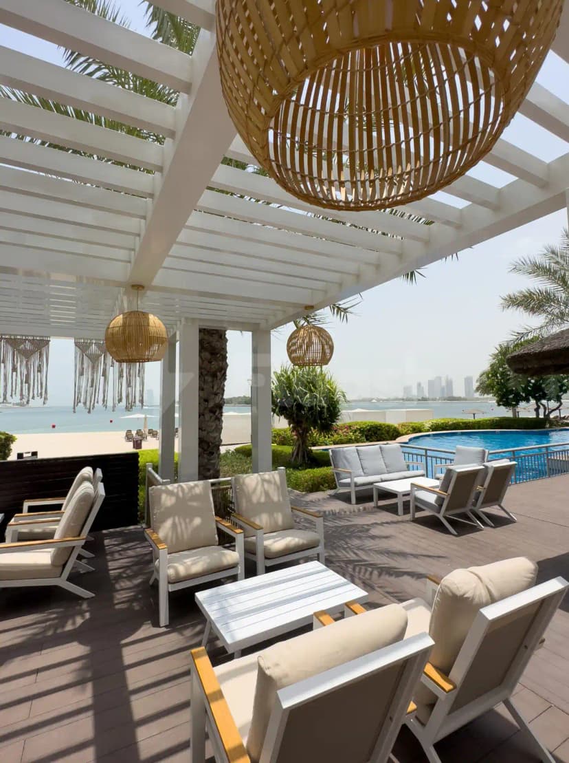 Rooftop terrace at Cabana On The Beach Palm Dubai with white pergola and wicker pendant lights
