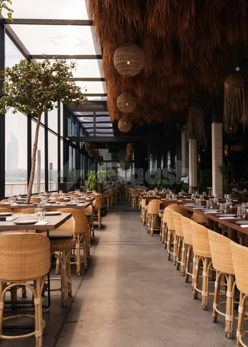 Open-air dining area at Bar Du Port Dubai with thatched ceiling and glass walls
