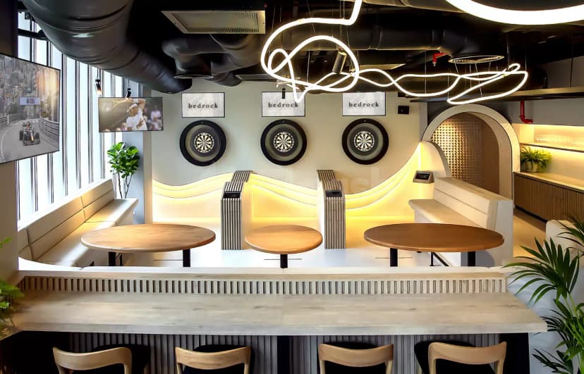 Games lounge at Bedrock Pier 7 in Dubai featuring dartboards and illuminated wave-shaped wall with white leather benches