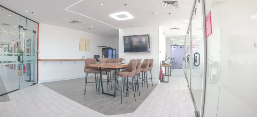 Restaurant area at Vision Work Space Jeddah featuring a high wooden table with brown upholstered stools