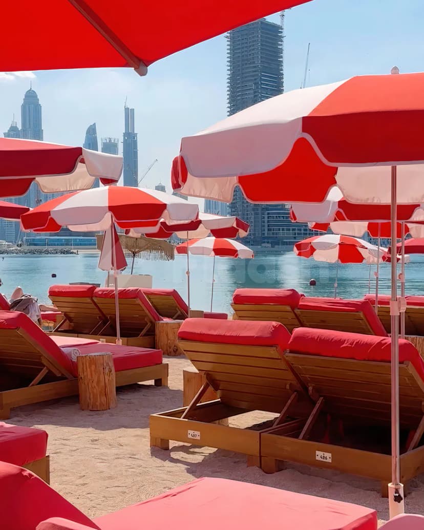 Beach at February 30 in Dubai with red and white umbrellas, wooden sun loungers, and a city skyline