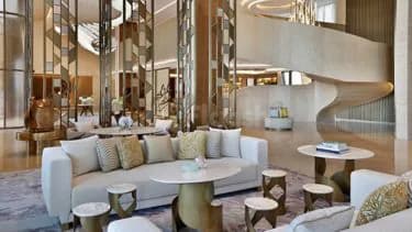 Entrance hall at The St. Regis Riyadh featuring a white sofa, gold-accented furniture, mirrored wall panels
