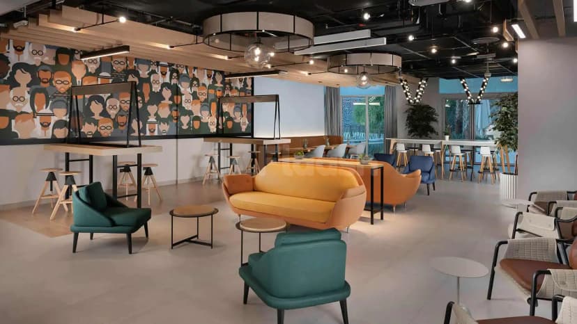 Modern lounge seating area at Rove Expo 2020 in Dubai featuring an orange velvet sofa and a large