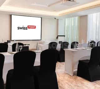 Meeting room at Swissotel Al Murooj Dubai featuring a white projection screen and black chair covers