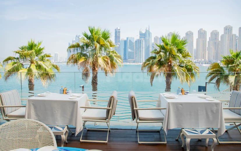 Rooftop terrace at Alici Restaurant Dubai with palm trees, glass railing, and a view of the Dubai skyline