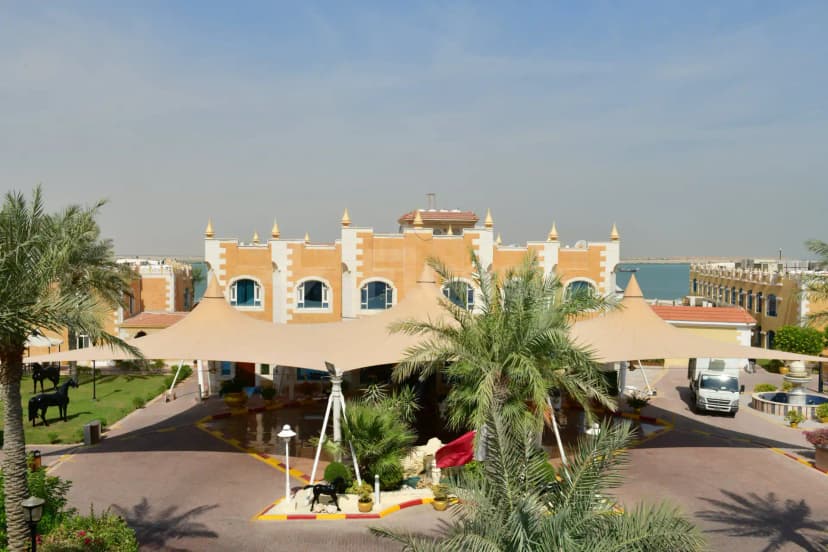 Beige tensile canopy at Tio Sea Resort Qatar in Doha, with palm trees and black horse statues flanking