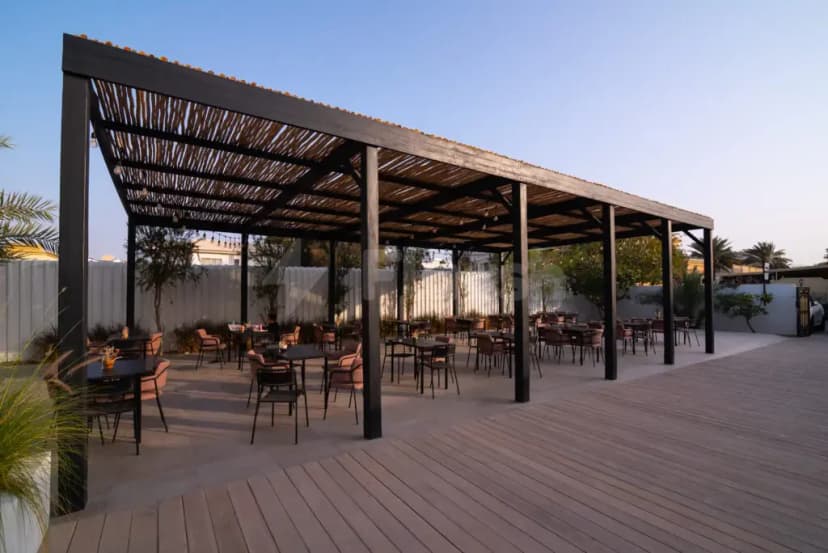 Rooftop terrace at Keyani Wellness in Dubai featuring a black metal pergola with woven reed roof and wooden