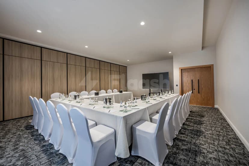 Meeting room at Intercity Hotel Riyadh with long table, white chair covers, wooden wall panels, and a flat
