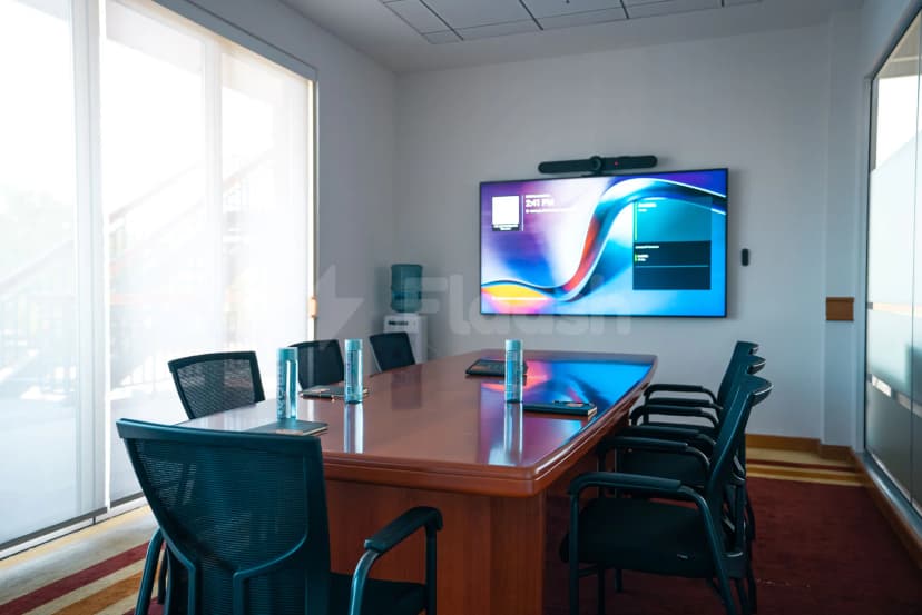 Boardroom at The Sevens Stadium in Dubai featuring a wooden table, black mesh chairs, and a wall-mounted TV