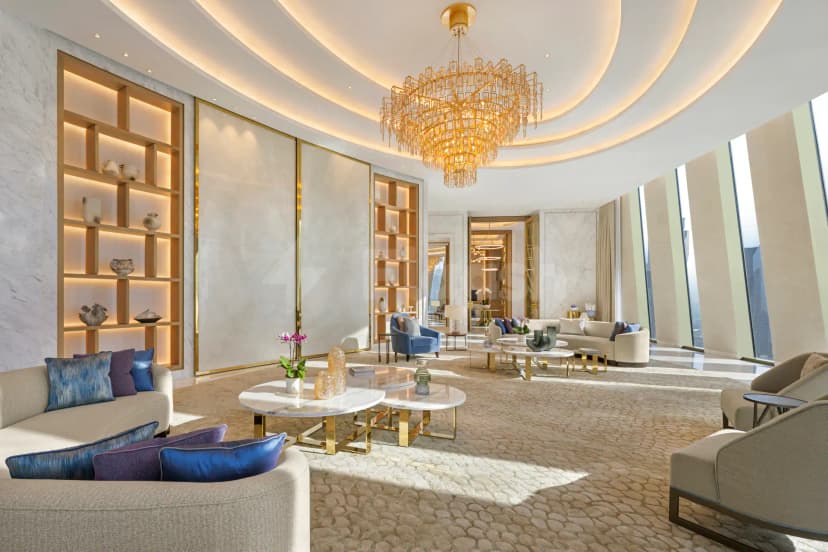 Entrance hall at Mandarin Oriental Downtown Dubai featuring a large gold chandelier and illuminated wooden shelving units