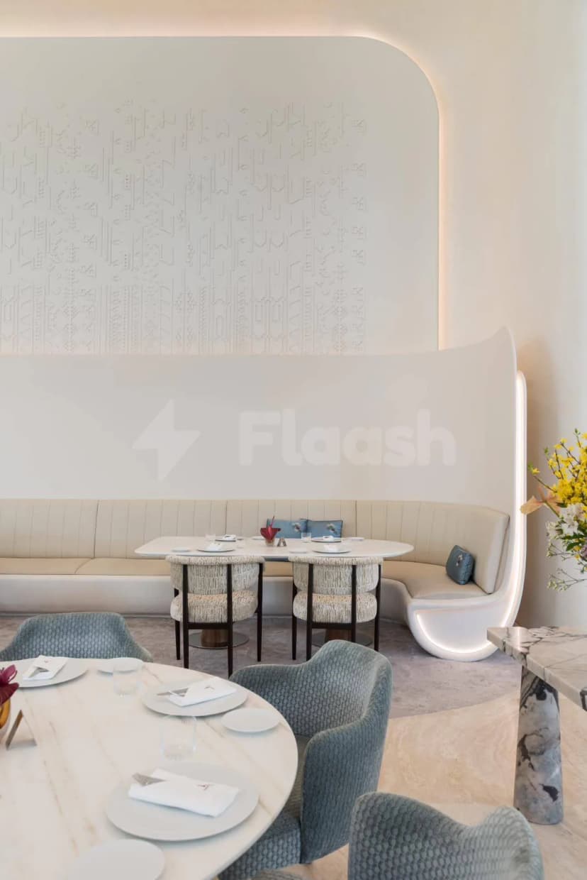 Restaurant interior at Sanad Lounge Doha featuring a beige upholstered booth and a white embossed wall panel