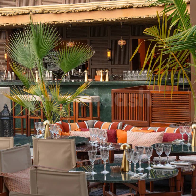 Ninive Bab Al Shams Restaurant Dubai features an outdoor dining area with green marble tables, palm plants