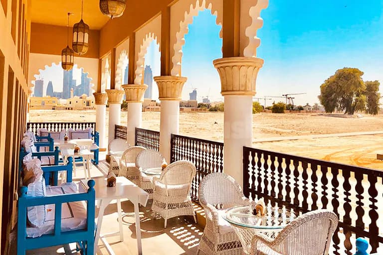 Rooftop terrace at Arabian Tea House Restaurant & Cafe Sharjah featuring ornate stone columns and arched openings overlooking desert