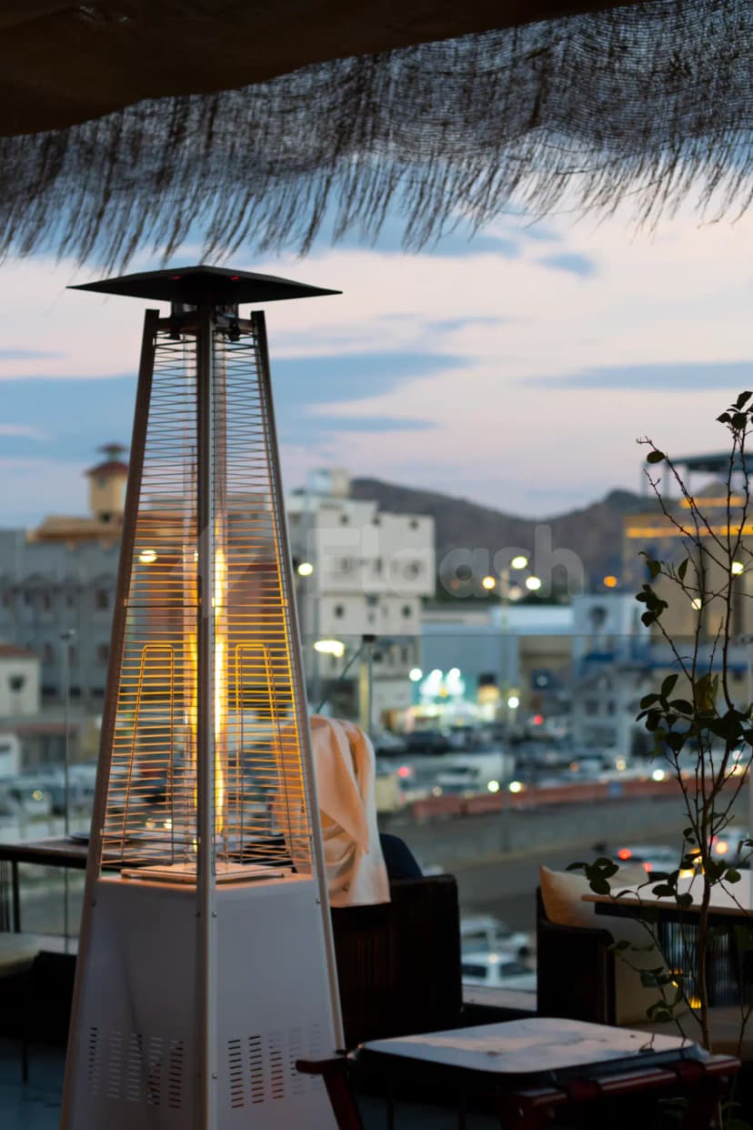 Rooftop terrace at Agape Restaurant & Cafe Taif in Taif with a tall gas heater glowing at dusk