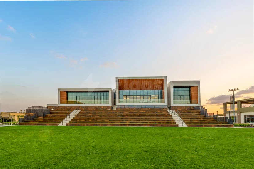 SEE Institute Dubai facade featuring modern glass and wood panels, tiered stone steps, and a green lawn under