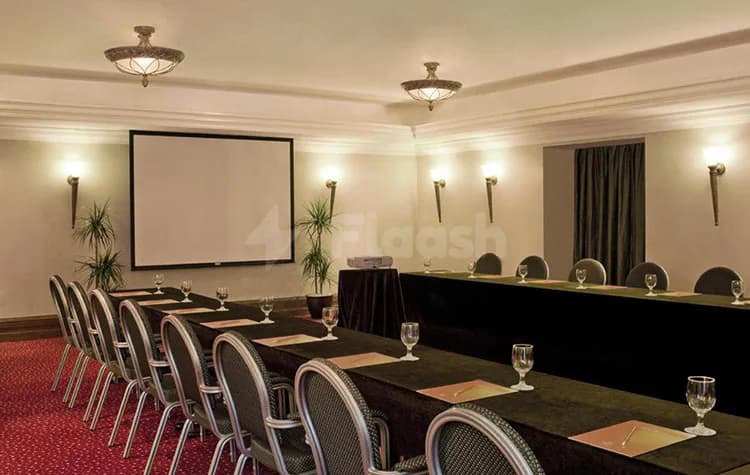 Meeting room at Sheraton Khalidiya Abu Dhabi featuring a long table with black tablecloth, grey mesh chairs
