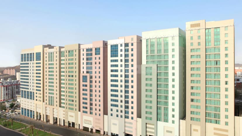 Hotel facade of Le Meridien Towers in Makkah featuring modern high-rise buildings with beige, pink, and white exteriors
