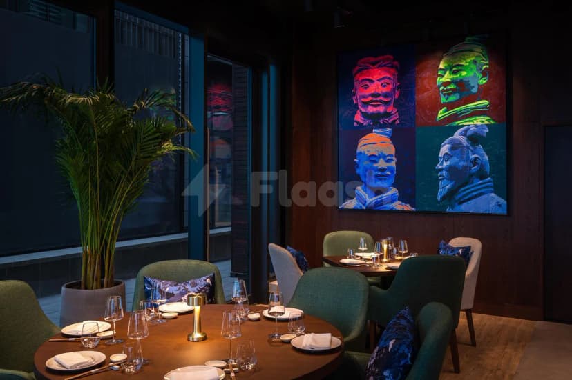 Shi Restaurant Dubai Marina dining room with round wooden table, green chairs, and vibrant Terracotta Warrior artwork