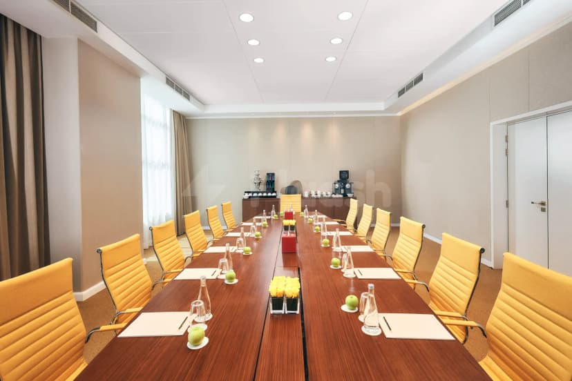 Boardroom at Shaza Riyadh featuring a long wooden conference table set with notepads, water bottles, green apples