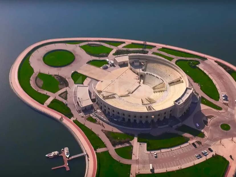 Circular amphitheatre at AlMajaz Amphitheatre Sharjah featuring tiered stone seating and a landscaped garden beside waterfront promenade
