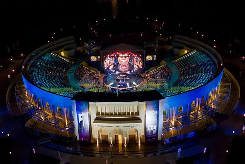 Circular amphitheatre layout at AlMajaz Amphitheatre Sharjah with tiered seating, central stage, large LED screen, and arched entrance