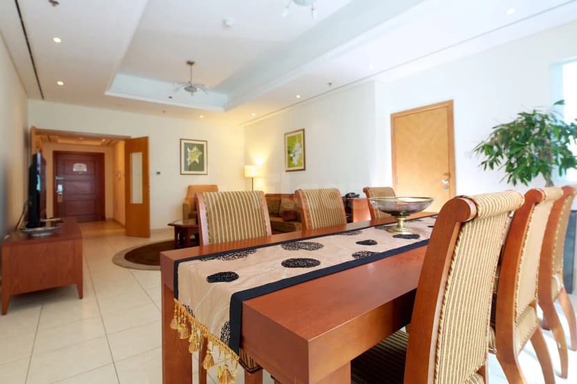 Meeting room at Tamani Hotel Marina Dubai featuring a wooden dining table with striped chairs and a beige