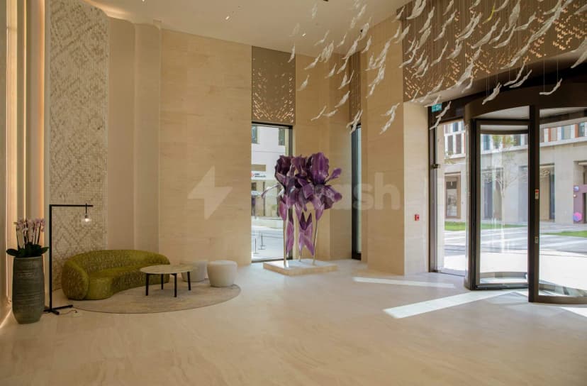 Entrance hall of Sanad Lounge Doha featuring a purple floral sculpture and hanging glass fish installation above light