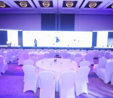 Ballroom at Jafza One Convention Centre in Dubai with round tables, white chair covers, and a large projection