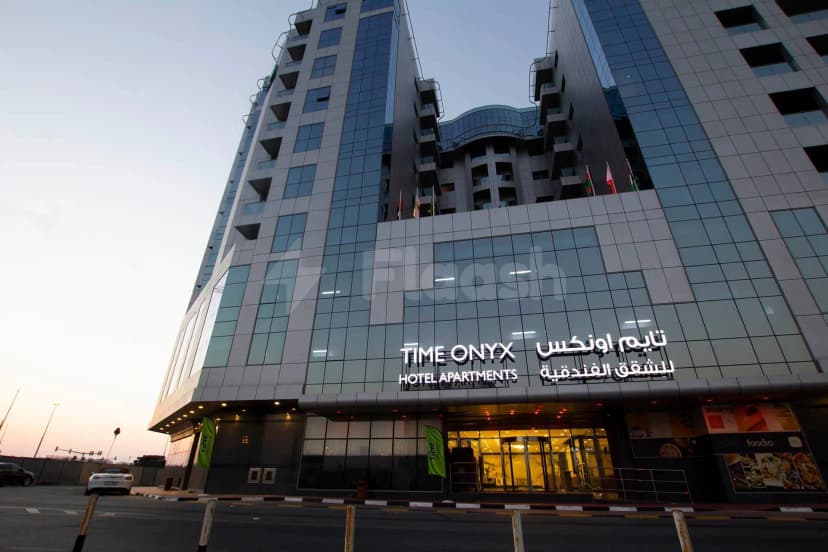 Hotel facade of TIME Onyx Hotel Apartments in Dubai featuring illuminated bilingual signage and a glass entrance