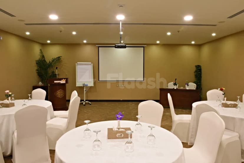 Meeting room at Garden Plaza Al Hafouf in Al Hofuf with round tables, white chair covers