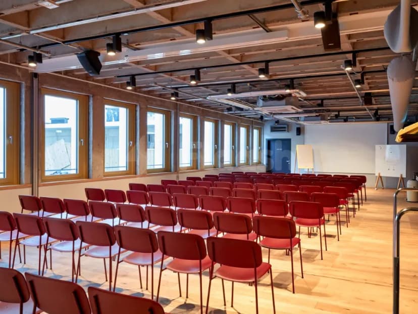 Meeting room at Ernst Biergarten Restaurant Dubai featuring rows of red chairs, large windows, exposed ceiling beams