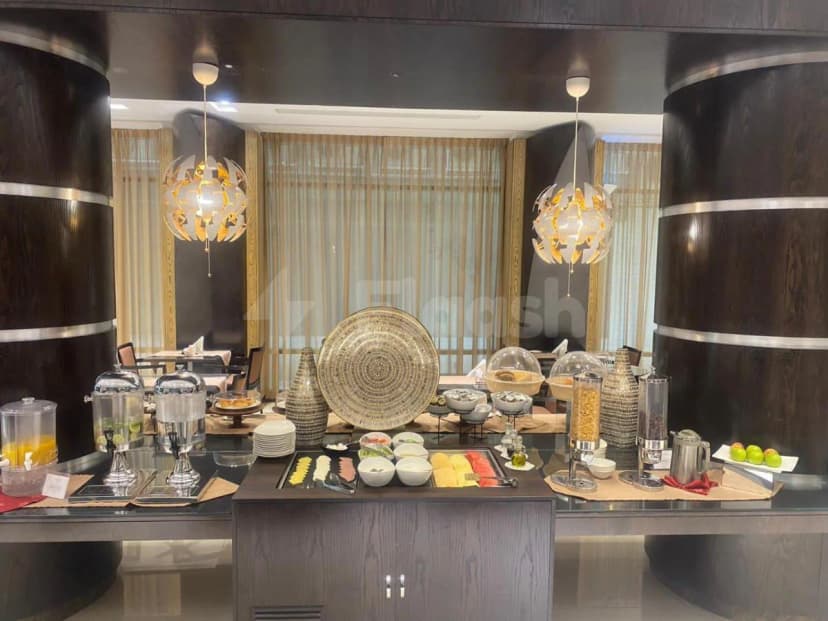 Restaurant buffet counter at Al Majaz Premiere Hotel Apartments in Sharjah featuring a dark wooden cabinet, glass countertop
