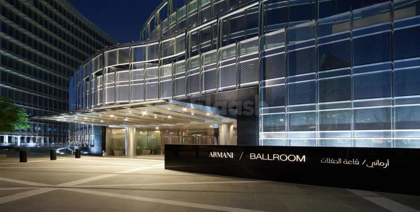 Hotel facade of Armani Hotel Dubai at night featuring a curved glass exterior and illuminated black sign reading