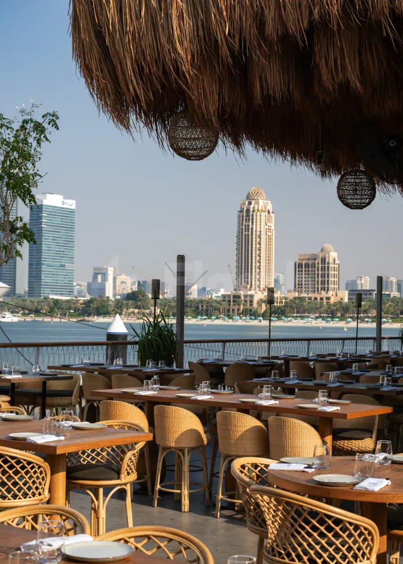 Rooftop terrace at Bar Du Port Dubai with thatched roof and hanging woven lanterns overlooking the waterfront