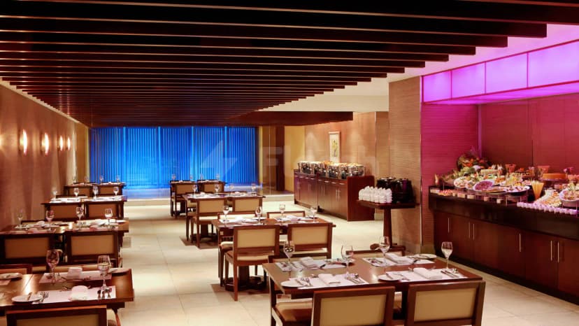 Restaurant at Le Meridien Towers Makkah featuring set dining tables, a buffet counter with chafing dishes, and blue