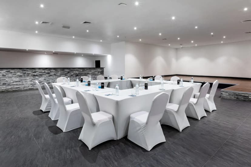 Meeting room at Bm Beach Resort Ras Al Khaimah with white-covered tables and chairs, stone accent wall