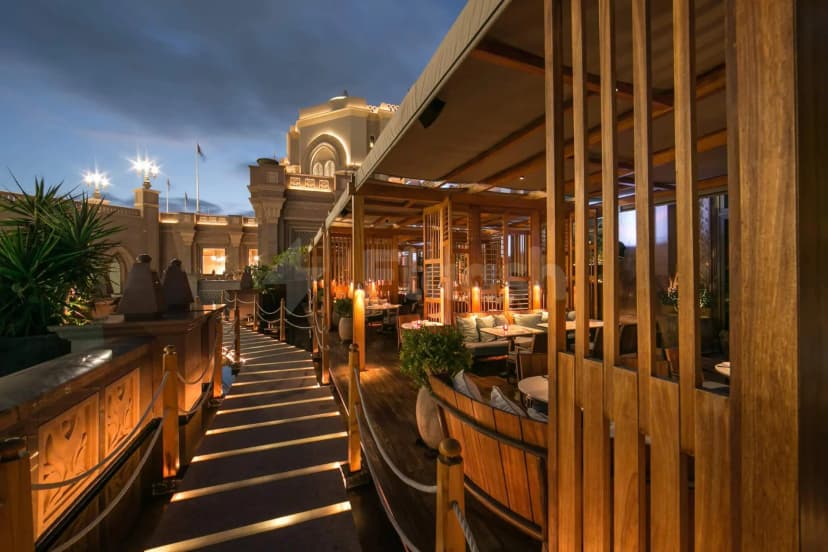 Rooftop terrace at Hakkasan Abu Dhabi featuring a wooden slat partition and illuminated walkway with rope railings under