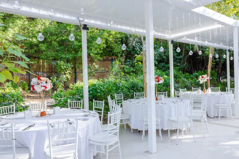 Terrace at The Farm Restaurant Al Barari in Dubai featuring a white pergola and round tables with floral