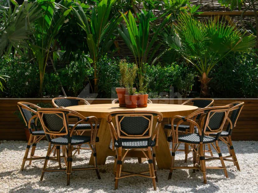 Terrace at Eugène Eugène Restaurant Dubai with round wooden table and tropical greenery backdrop