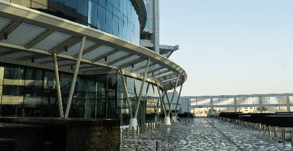 Modern glass facade of Jafza One Convention Centre in Dubai with curved metal canopy and white support columns