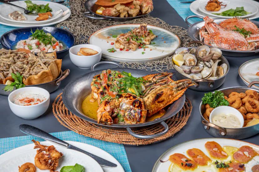 Ibn AlBahr Seafood Restaurant in Dubai features a seafood platter with grilled prawns and crab on a woven