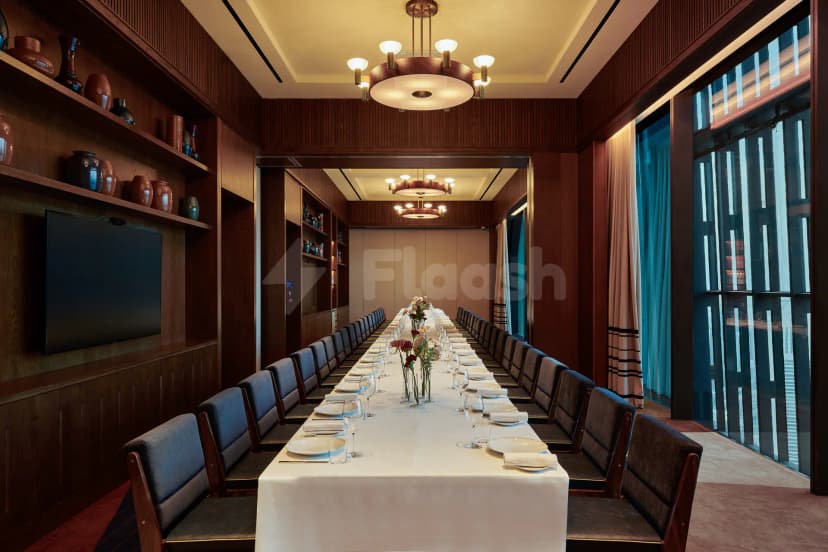 Meeting room at ICD Brookfield Place Dubai featuring a long rectangular table with white tablecloth, blue upholstered chairs